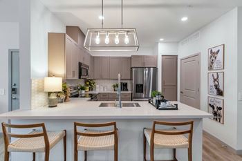 an open kitchen with a large island with three stoolsat Weylyn Luxury Apartments, Laveen, AZ 85339
